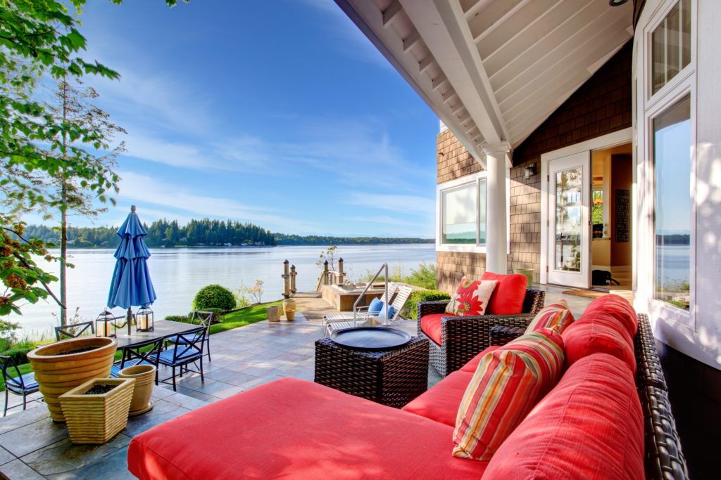 Luxury Outdoor Patio Waterside Room with Red Couch and Colorful Pillows